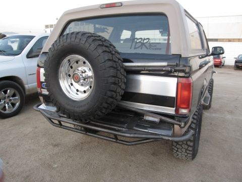 1986 Ford Bronco - This Ford Bronco features a spare tire on the rear, a custom bumper, and a sticker indicating it participated in the Baja 1000.