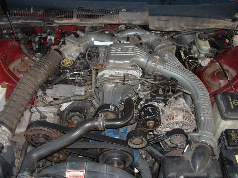 1991 Ford Thunderbird - Close-up view of a V8 engine bay, showing the air intake system, alternator, and various hoses and belts.
