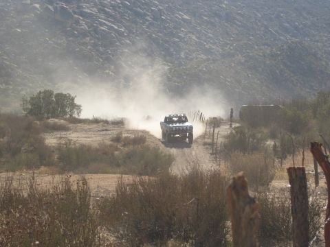 1986 Ford Bronco - A modified truck races down a dusty trail in a remote, arid landscape.