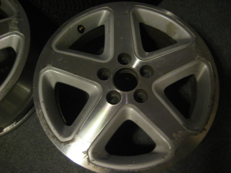 Close-up of a silver 5-spoke alloy wheel with some scuff marks