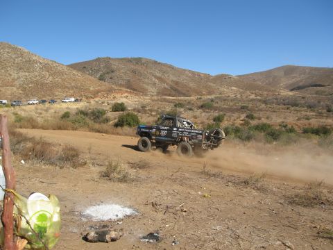 1986 Ford Bronco - Modified 1986 Ford Bronco racing off-road, kicking up a cloud of dust on a dry, hilly course.