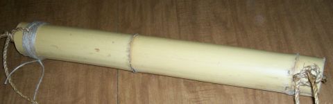 1993 Ford Bronco - A handmade bamboo quiver laid on a dark wood surface, showing the pale yellow bamboo tube with natural nodes, twine wrapping at the closed…