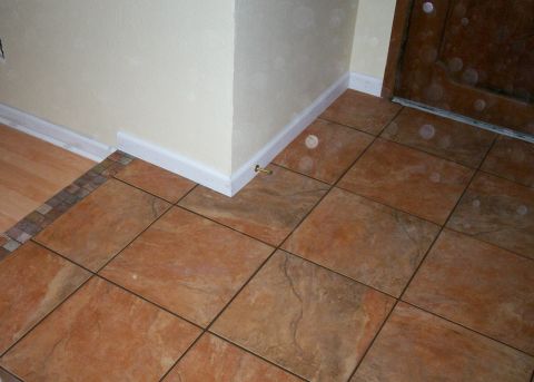 1993 Ford Bronco - Finished home entryway floor showing large terracotta-toned stone-look ceramic tiles laid on the diagonal, edged with a mosaic accent strip…