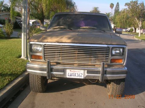 1985 Ford Bronco - Frontal view of a weathered 1980s Ford Bronco parked on a residential street.