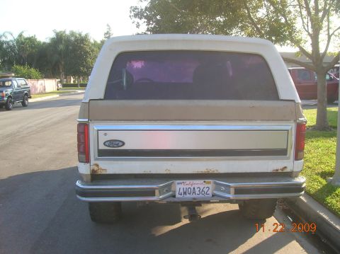 1985 Ford Bronco - Rear view of a Ford Bronco, with another Bronco parked on the left side of the street.