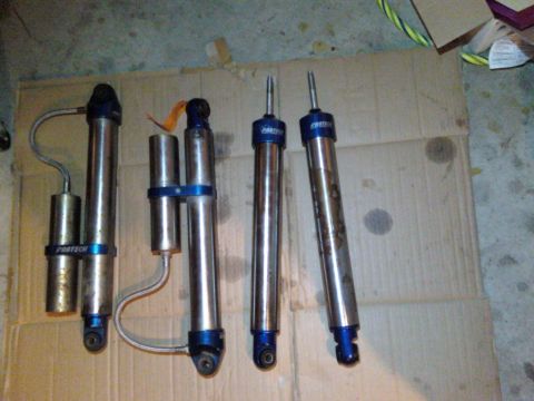1984 Ford Bronco - Four shock absorbers, two with external reservoirs, are shown on a cardboard surface.