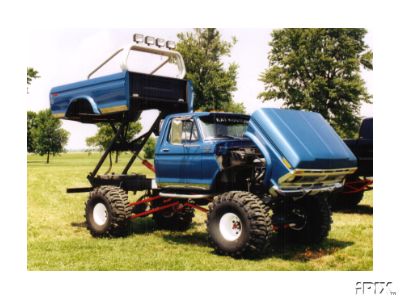 2002 Ford F-350 - This heavily modified blue pickup truck features a lifted suspension and its bed is elevated above the cab.