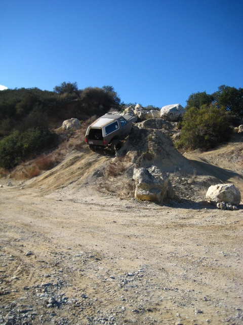 1989 Ford Bronco - A vehicle navigates a challenging rocky terrain under a clear blue sky.