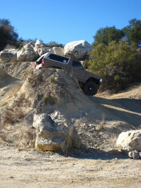 1989 Ford Bronco - This 1980s Ford Bronco navigates a steep, rocky incline under a clear blue sky.