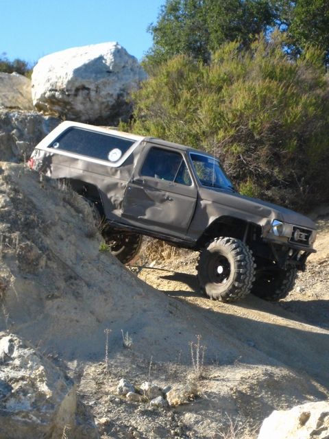 1989 Ford Bronco - This heavily modified 1980s Ford Bronco is navigating a challenging off-road trail.