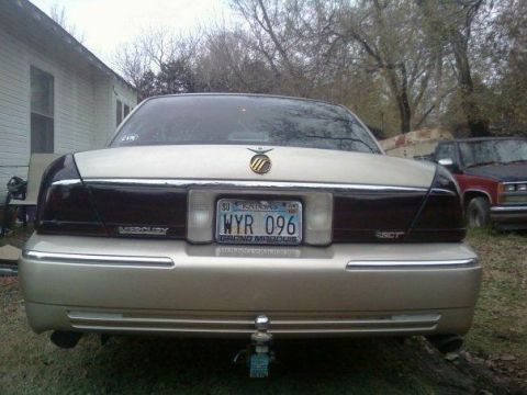 2000 Mercury Grand Marquis - Gold 2000 Mercury Grand Marquis seen from the rear, parked outdoors with another vehicle nearby.