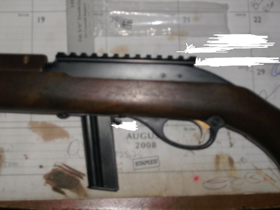 Wood-stocked rifle action with magazine and scope rail on a 2008 calendar.