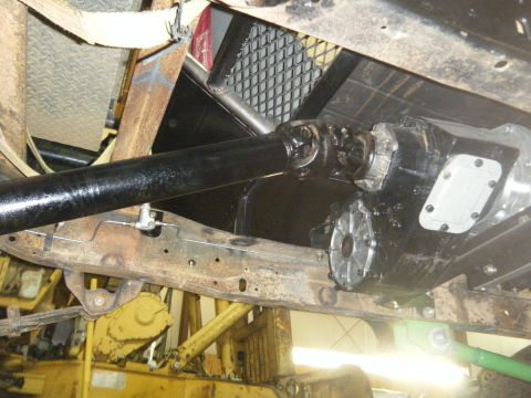 1978 Ford Bronco - The underside of a vehicle shows its transfer case and driveshaft, with visible rust on the frame.