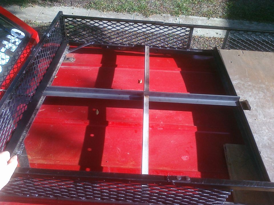 red trailer bed with metal cross supports, part of a red vehicle visible on left