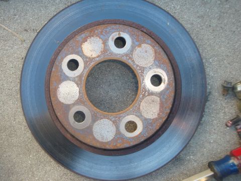 1995 Ford Taurus - A rusty brake rotor is shown, with some tools nearby. The condition suggests it may need replacement.