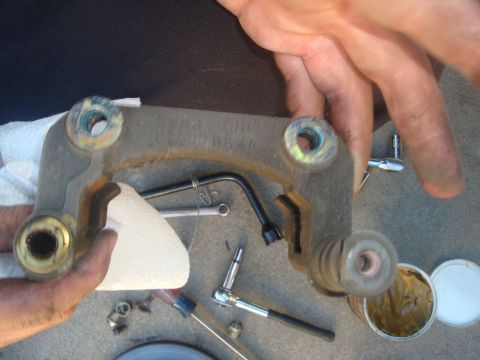 1995 Ford Taurus - A brake caliper bracket is shown with tools and grease, indicating a repair or maintenance activity.