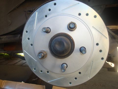 1995 Ford Taurus - A drilled and slotted brake rotor is shown installed on a vehicle's hub.