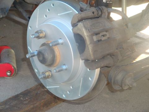 1995 Ford Taurus - A Ford brake caliper is shown mounted over a new slotted and drilled rotor.