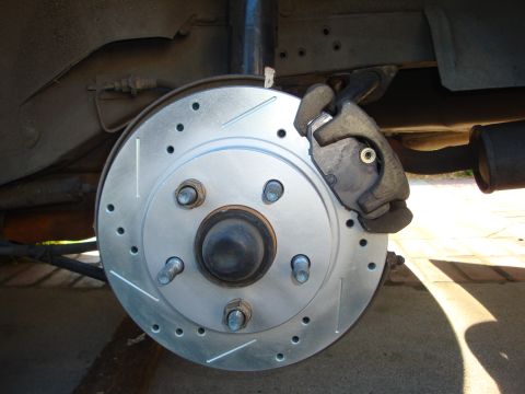 1995 Ford Taurus - Close-up view of a rear brake assembly a drilled and slotted rotor and a caliper.
