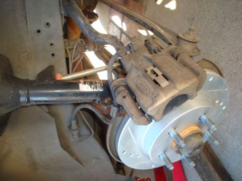 1995 Ford Taurus - A close-up view of a vehicle's rear brake assembly, a Ford caliper and a newly installed drilled rotor.