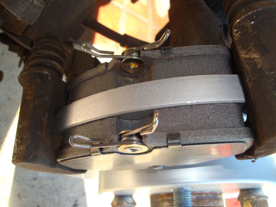 Close-up of a brake caliper with new pads and retaining clips
