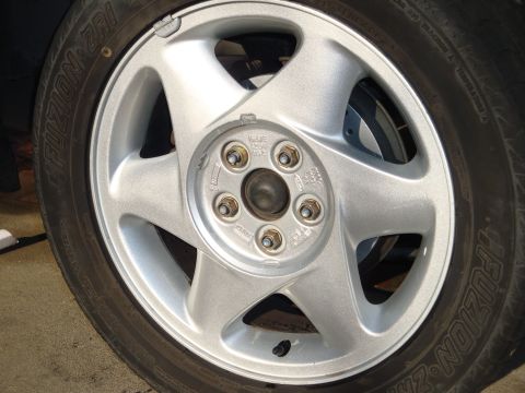 1995 Ford Taurus - A close-up view of a vehicle's wheel and tire assembly, showing the silver alloy rim and tire tread.