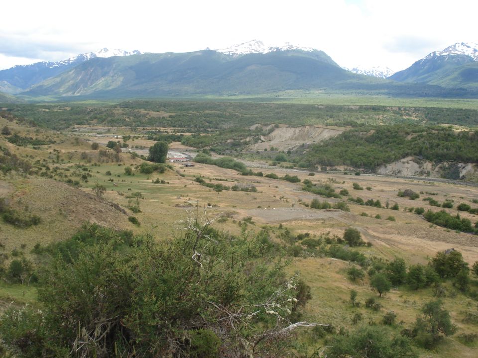 Scenic valley with snow-capped mountains under a cloudy sky