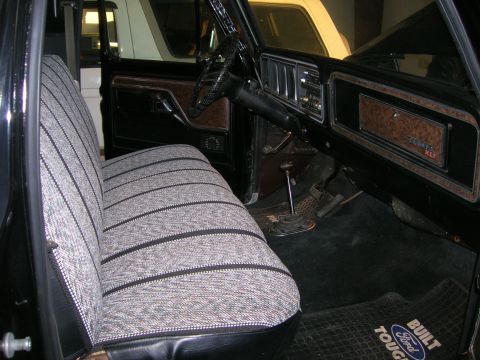 1975 Ford F-250 - The interior of a 1975 Ford F-250 features a patterned bench seat and wood-grain trim on the dashboard.