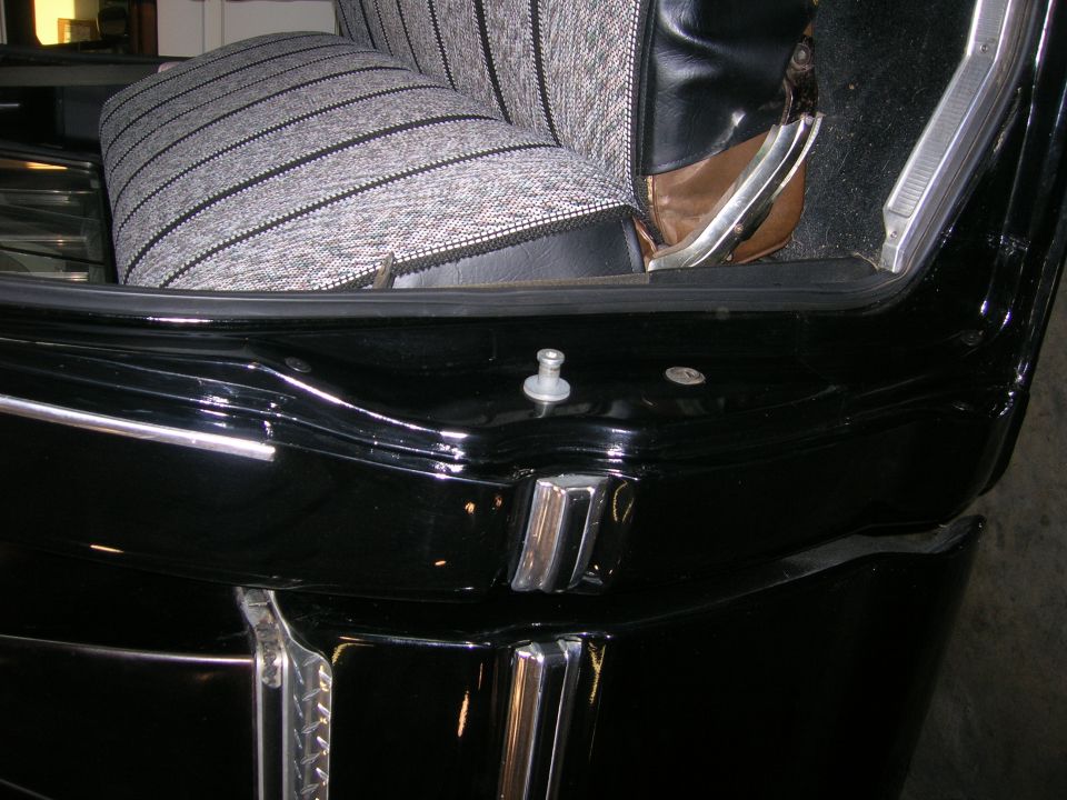 Black vehicle interior showing striped seat fabric, door jamb, and chrome trim