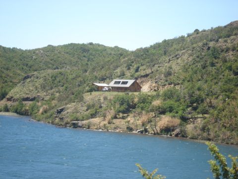 1986 Ford Bronco - A white SUV is parked on a hill next to a house with a large roof, overlooking a body of water.