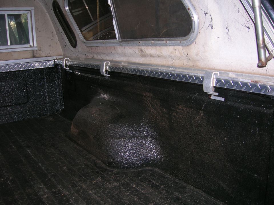 Interior of a 1975 Ford F-250 truck bed with a camper shell