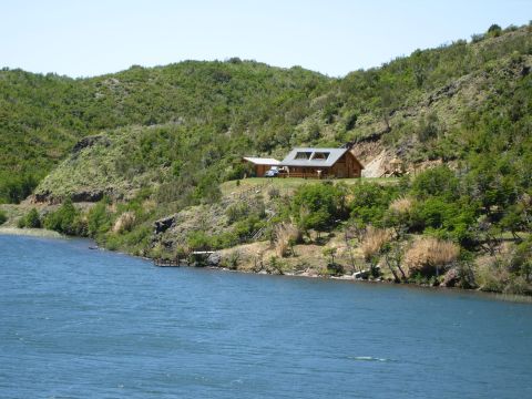 1986 Ford Bronco - A blue SUV is parked near a log cabin on a hillside overlooking a lake.