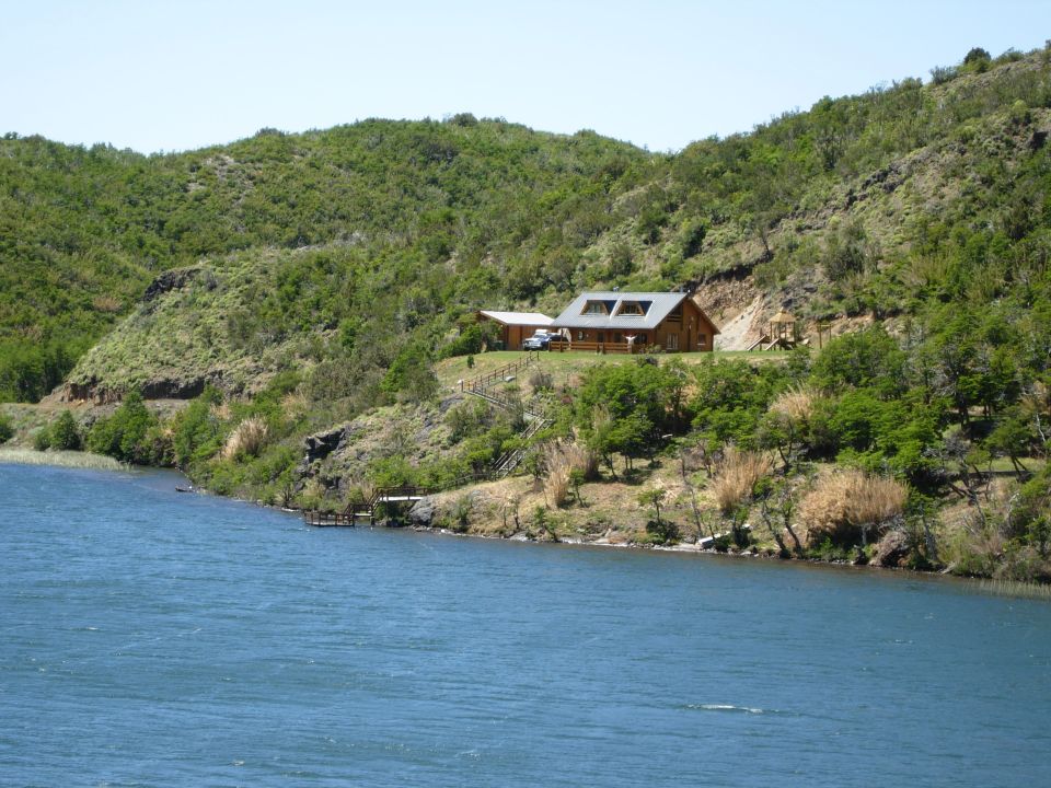 Blue SUV parked near a log cabin by a lake