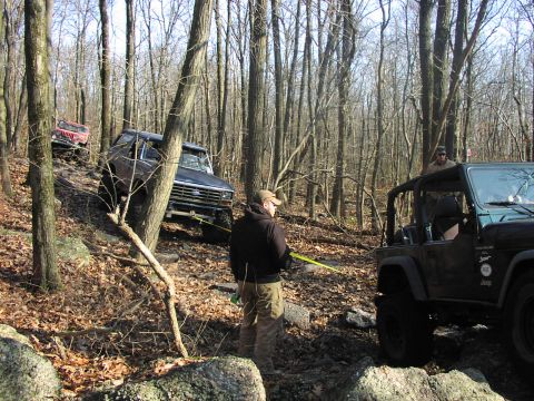 1986 Ford Bronco - A dark blue Ford Bronco navigates a challenging off-road trail with other vehicles present.