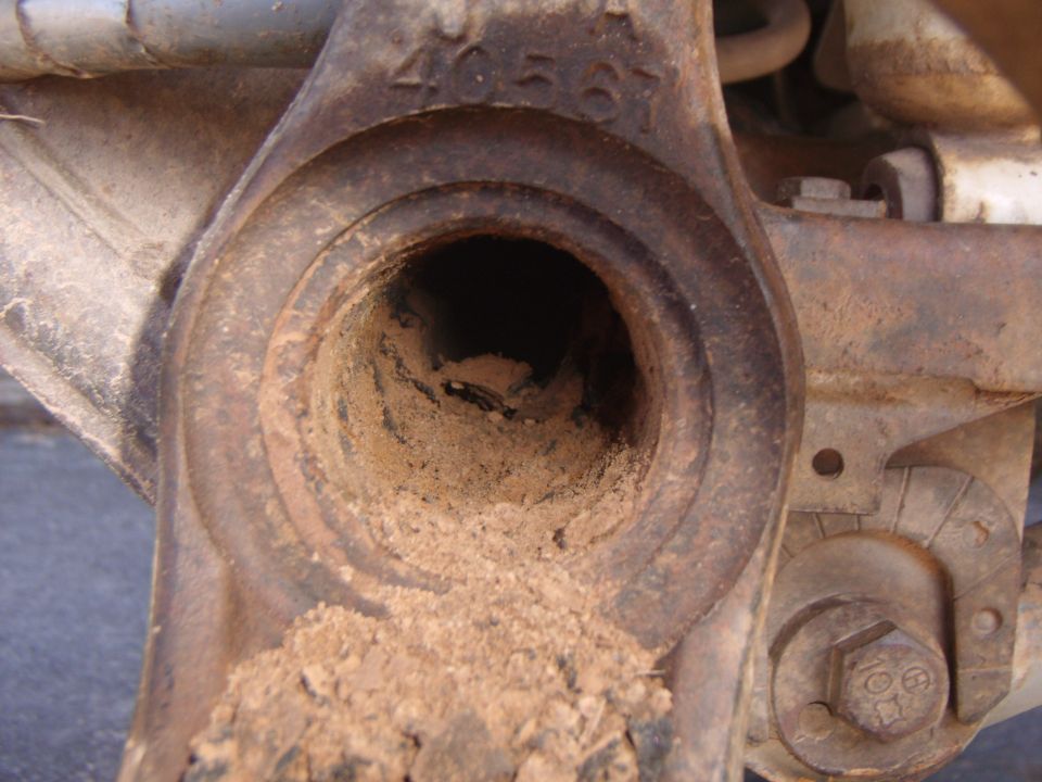 Close-up of a rusty, dirt-filled suspension component with visible numbers '40567'