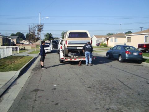 1986 Ford Bronco - A tan and white Ford Bronco is being loaded onto a trailer in a residential neighborhood.