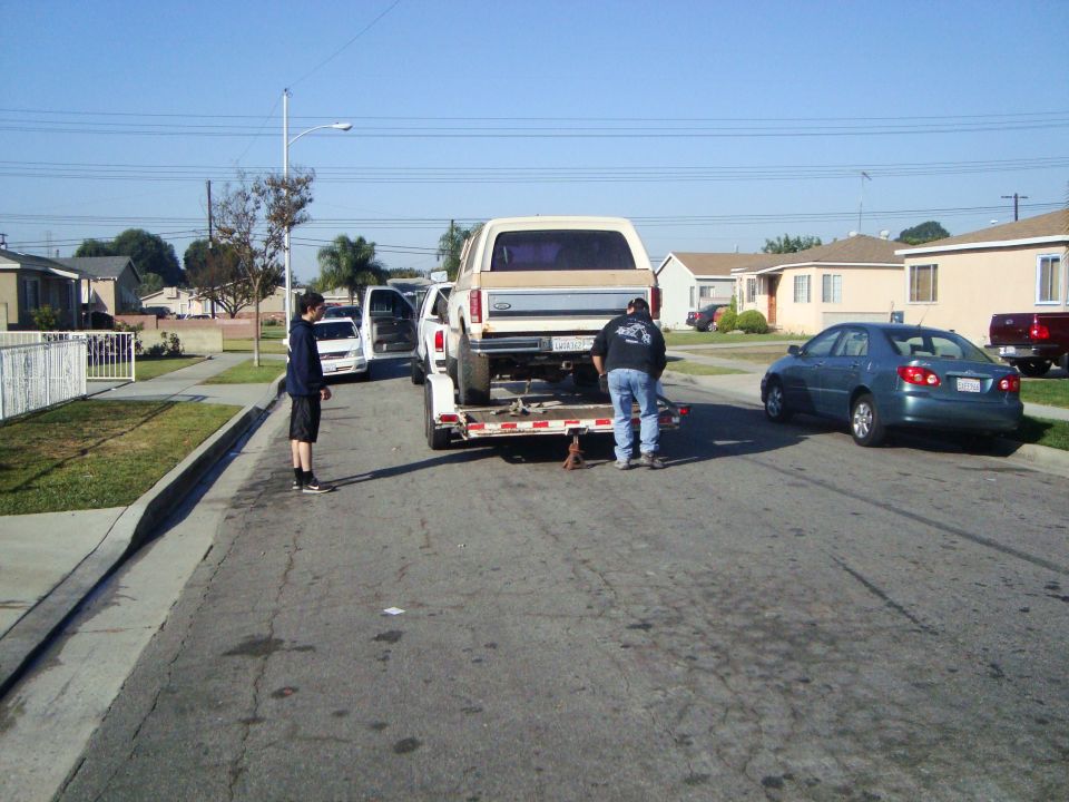 Rear view of tan and white Ford Bronco on trailer, being loaded