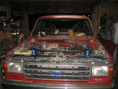 1990 Ford Bronco - Front view of a red 1990 Ford Bronco with its hood open, revealing the engine and interior roll cage.