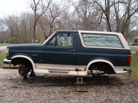 1993 Ford Bronco - A 1993 Ford Bronco is shown on jack stands with its wheels removed, undergoing maintenance or repair.
