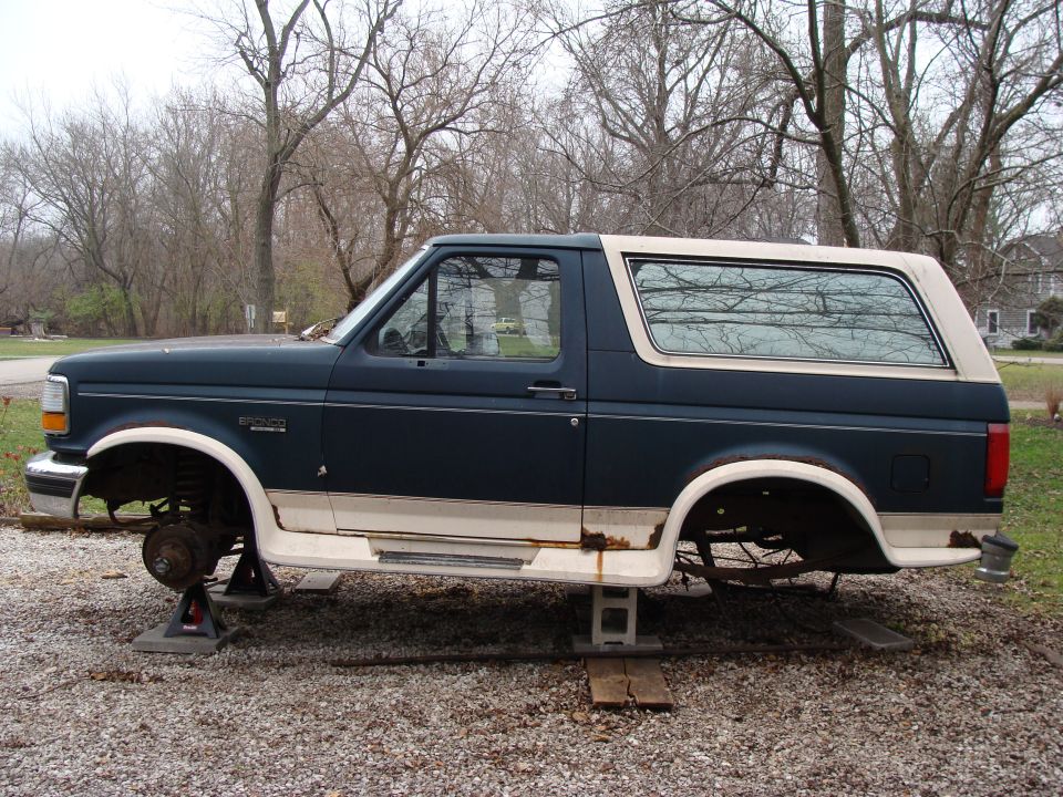 Side view of a 1993 Ford Bronco on jack stands, missing wheels