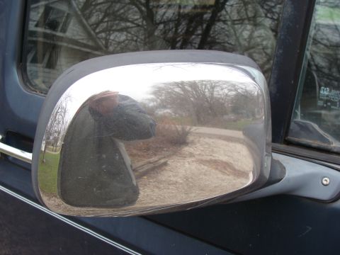 1993 Ford Bronco - Side mirror with chrome trim on a dark-colored vehicle.
