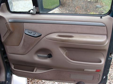 1993 Ford Bronco - Close-up of a vehicle's interior door panel, showing the window controls and storage compartments.