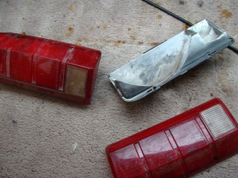 1993 Ford Bronco - Red taillight assemblies and a silver housing are laid out on a carpeted surface.