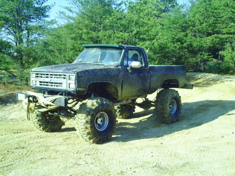 1990 Ford Bronco - This heavily modified pickup truck features oversized tires and a lifted suspension, suggesting off-road use.