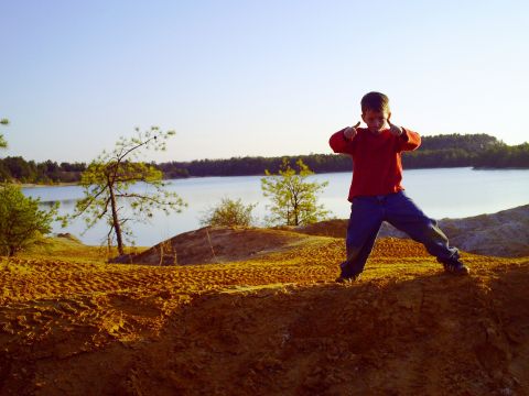 1990 Ford Bronco - A young boy stands on a sandy embankment, giving a double thumbs-up with a lake and trees in the background.