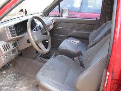 1993 Isuzu Rodeo - The interior of a vehicle is shown, with a view of the dashboard, steering wheel, and seats. Another vehicle is reflected in the side mirro…