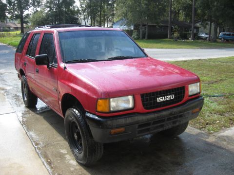 1993 Isuzu Rodeo - This red 1993 Isuzu Rodeo SUV is shown from the front 3/4 angle on a wet surface.