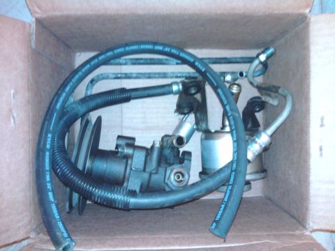 1983 Ferrari Enzo - A power steering pump with hoses is pictured inside a cardboard box, likely for sale or shipping.