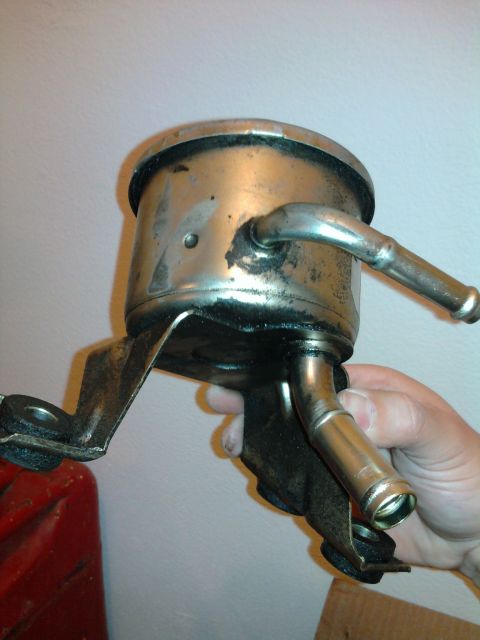 1983 Ferrari Enzo - A metal oil filter housing with attached metal hoses is held in a hand.