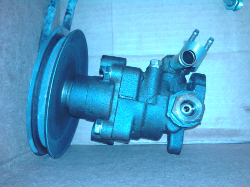 Cast aluminum power steering pump with V-belt pulley and hex pressure port on cardboard